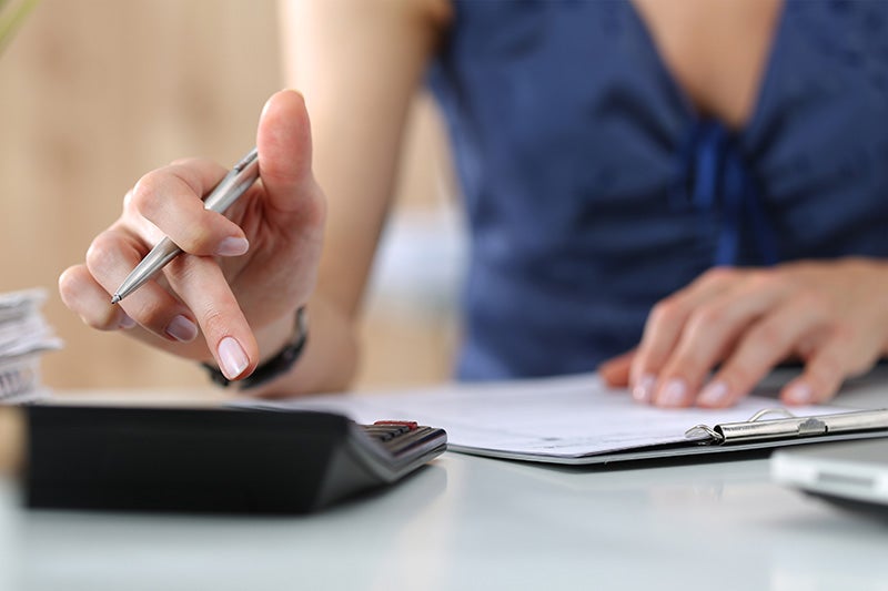 Young woman holding a pen and using a calculator